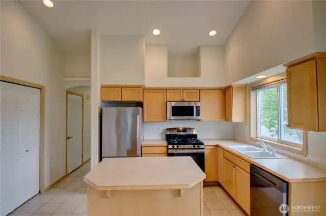 Kitchen looking towards front entry hallway, showing double door pantry, door to half bath.