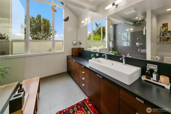The primary bath combines spa-like comfort with clean contemporary lines, featuring a broad vanity with vessel sink, walk-in shower, and walls of glass that brighten the space with treetop views. Every detail balances privacy with the natural serenity of Olmsted’s park.