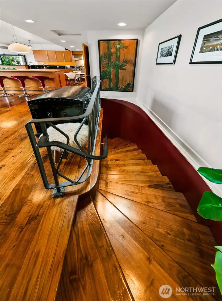 A dramatic serpentine stair curves downward, its walnut treads and sculptural lines carrying the home’s rich materiality into the garden level. This graceful transition links main-floor living to versatile suites and workspaces below.