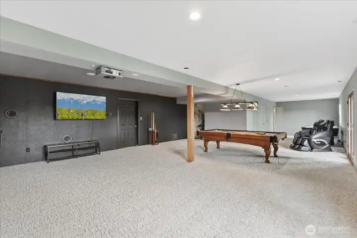 The door in the background opens to a large, 27' x 7' storage room that holds the propane furnace and water heater. Yes, those are mounted speakers and projector convey with the home. The pool table is negotiable
