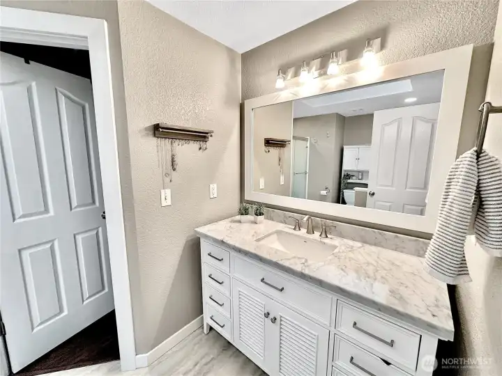 Lovely primary bath features ample vanity, laminate flooring, access to walk-in closet.