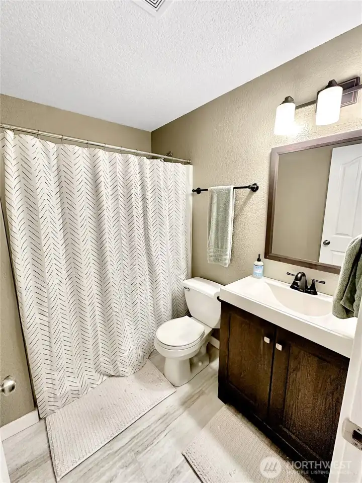 Updated hall bath with laminate flooring, stylish vanity and lighting.