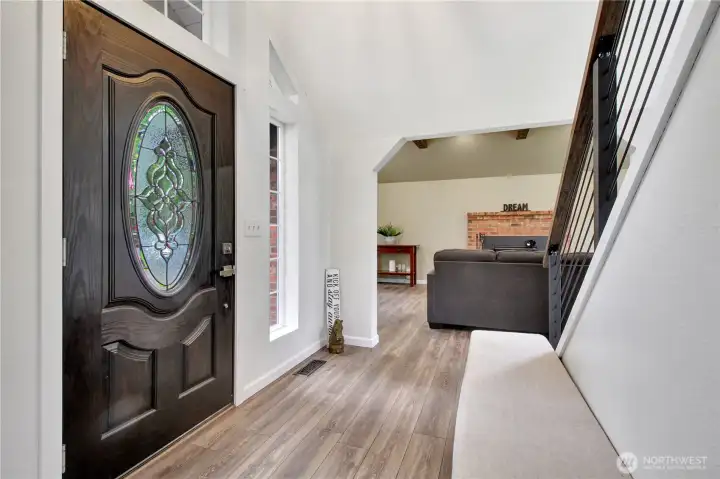 Entry has soaring ceilings with a wall of windows behind the stairwell to the second level.
