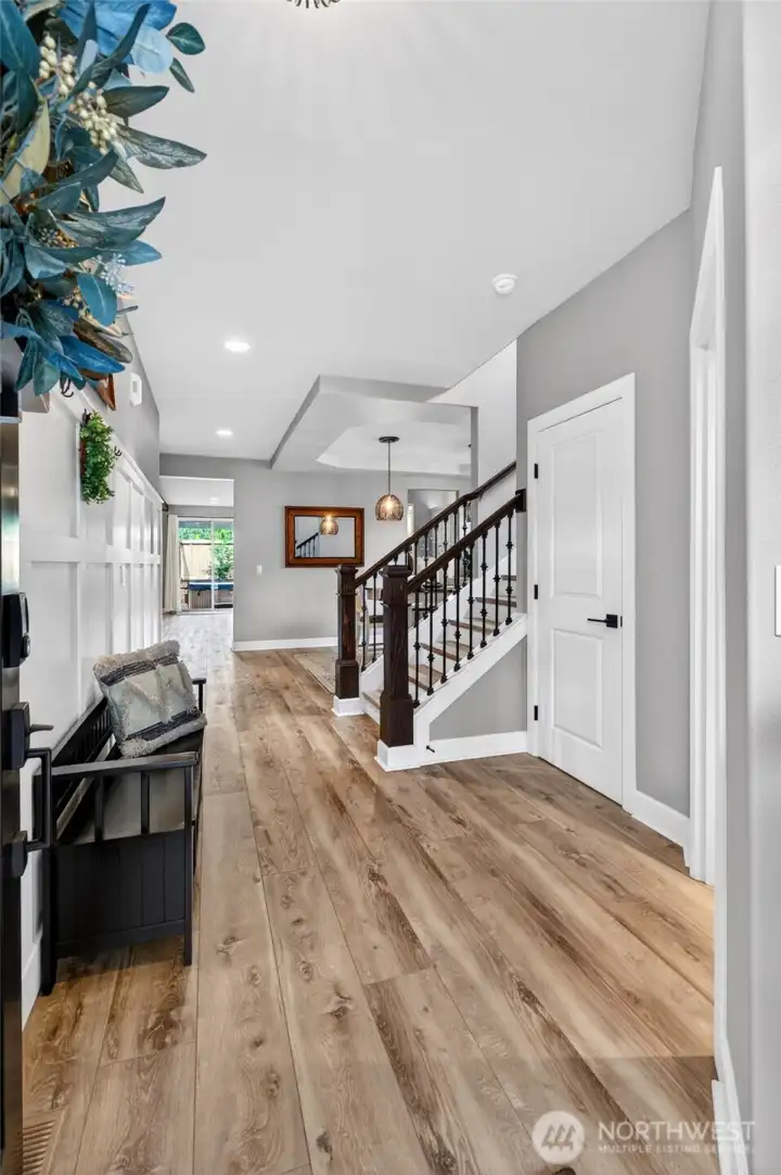 Stunning entryway with beautiful LVP, large wrap-around 'under the stairs' coat closet, beaming natural light, and board & batten accent wall.