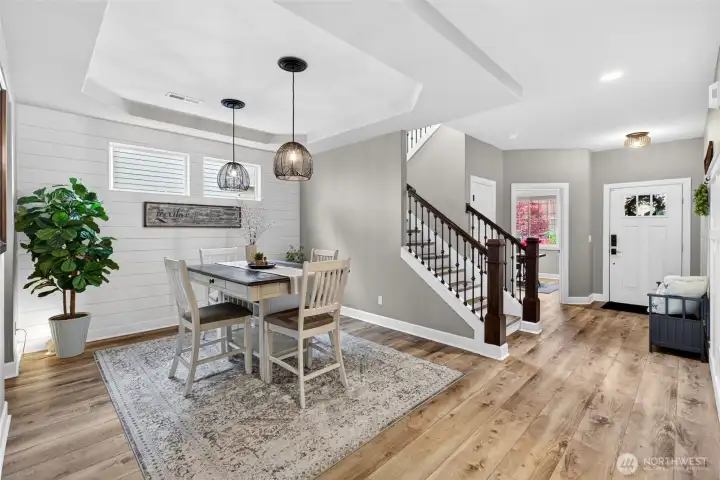 Formal dining space features tray ceiling, custom pendant lighting, and shiplap accent wall.