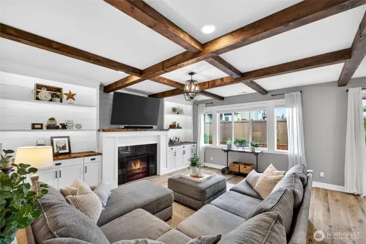 Beautiful living room easily fits a large sectional and features custom built-in shelving with cabinets for extra storage. All topped off with gas fireplace, faux beams and accent lighting!