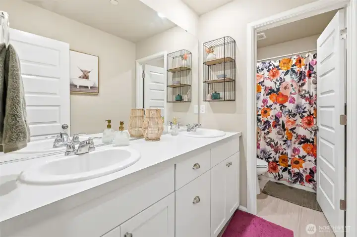 Hall bath features dual sinks and a separate bathing/toilet area for flexibility.