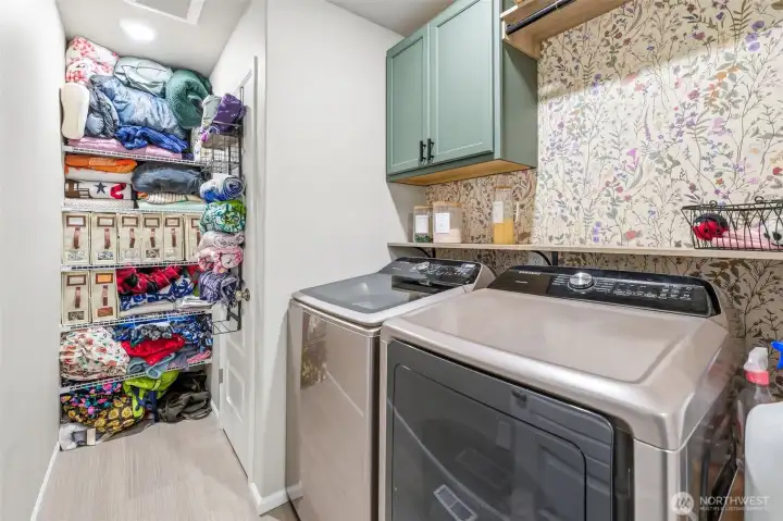 Upstairs laundry features custom cabinets and extra storage