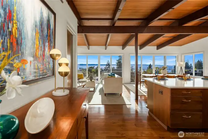 Front entry of home framed by sweeping view of Puget Sound. Entry contains original slate floors before transitioning to hardwoods. Kitchen to the right. Walk-in pantry with large wine fridge to the left.