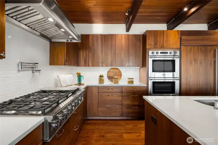 DCS by Fisher & Paykel six-burner plus flattop range with professional quality ventilation. DCS by Fisher & Paykel double oven. Under cabinet accent lighting. Pot filler above stove.