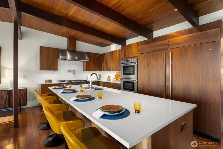 Wide shot of open concept kitchen perfect for entertaining and appreciating the view while cooking. Walk-in pantry is across from island.