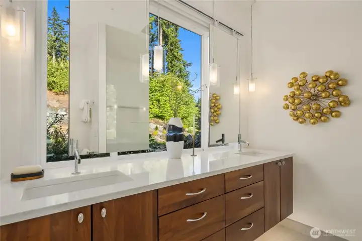 The primary bathroom includes a floating mirror with plenty of natural light, perfect for applying makeup. Automated electric blinds sit between window and mirrors to provide privacy when necessary.  Bathroom also has private water closet, and porcelain tile shower with LED accent lighting.