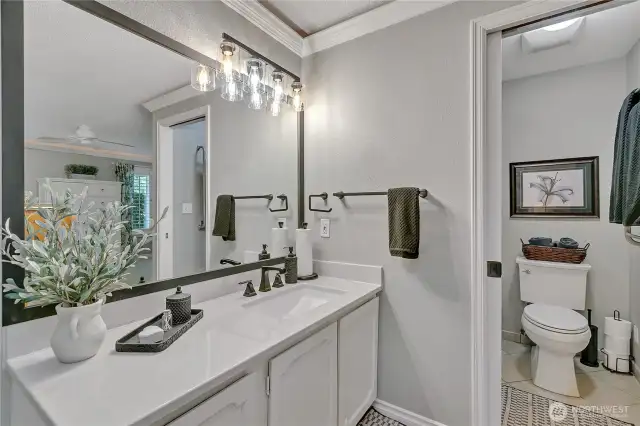 Primary bath updated 2025.  Solid surface vanity-sink combination.  Note continued crown molding. Doorway to separate toilet and shower.