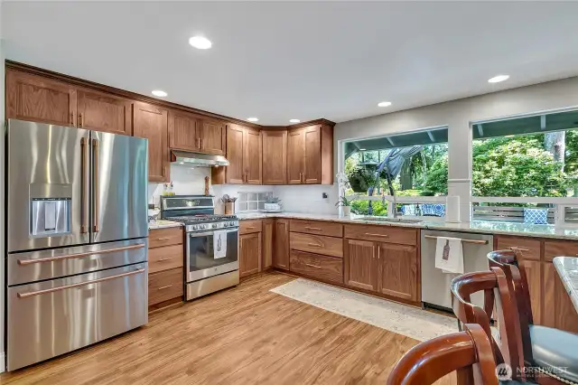 Black walnut cabinetry. Kitchen window out to deck and golf course beyond.  LVP flooring for ease and beauty. Milgard Windows. Windows large as can be for natural light + canned lights as well!