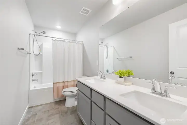 Guest bath with dual vanities, centrally located upstairs.