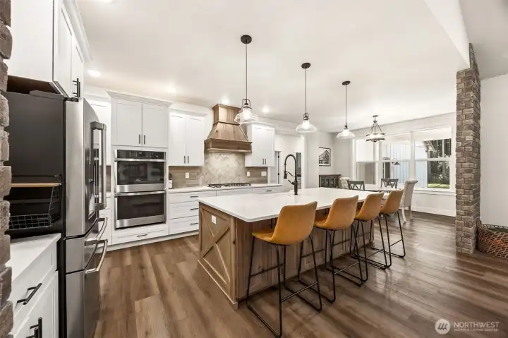 Brick accents, warm wood tones, expansive island & stunning range hood, tile backsplash, Luxury Vinyl Flooring, Butler's Pantry, dining nook, also an adjacent dining room.