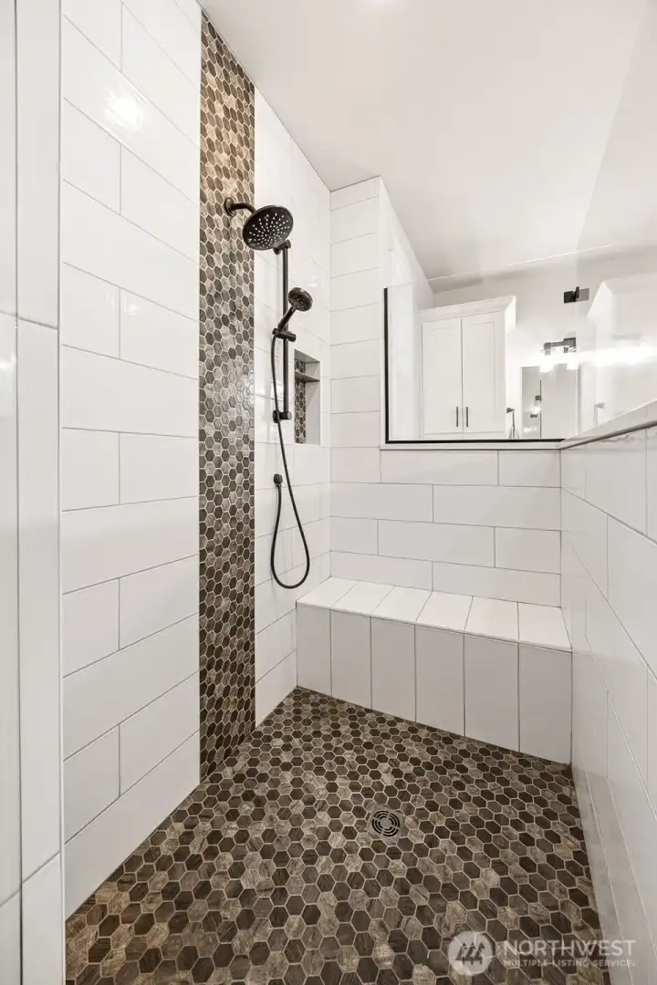 Luxurious fully-tiled walk-in shower of primary bathroom.
