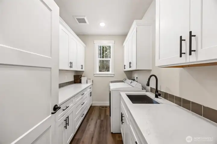 This laundry room has the capacity to handle it all right here, expansive counter space with sink & abundant storage.