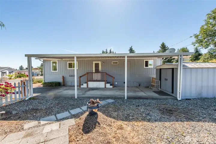 Part of the yard looking at the back door and carport with storage shed. Part of the yard looking at the back door and carport with storage shed.
