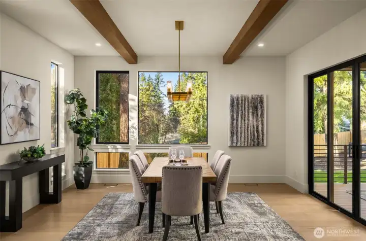 Large dining room with wood beam accents and floor to ceiling windows