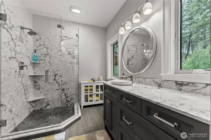 Quartz counters and shower surround and ceramic tile in the sleek and modern primary bath.