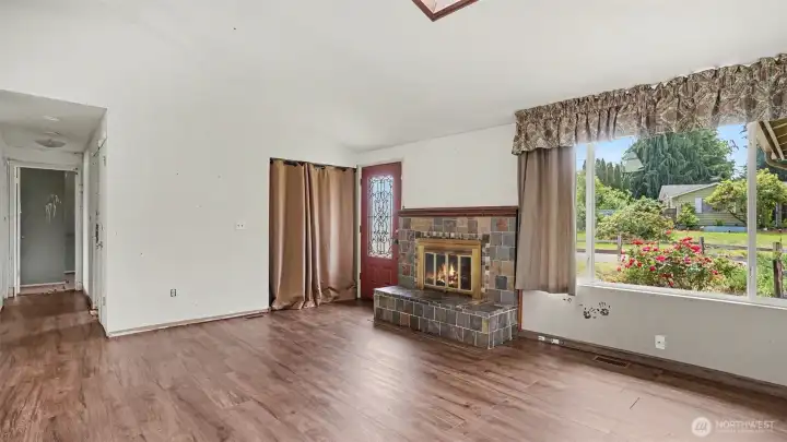 Inside, vaulted ceilings and a skylight create a bright and airy atmosphere, while a cozy fireplace anchors the main living space.