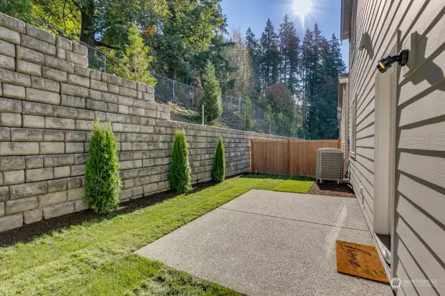 A peaceful fully fenced and landscaped backyard borders a green space for privacy.