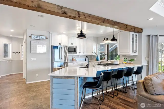 Gorgeous open kitchen with white cabinets and countertops and seating area.