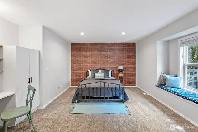3rd bedroom with brick accent wall and cozy window seat.