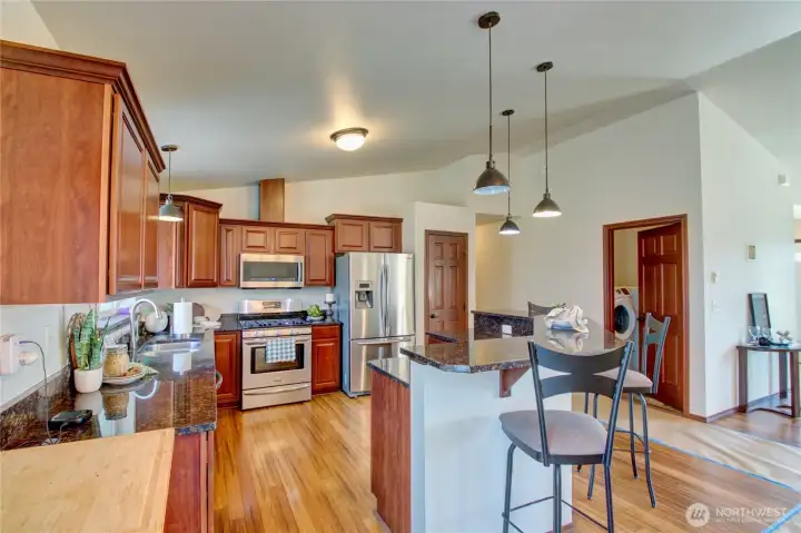 Kitchen with granite countertops, eating bar, stainless steel appliances, gas range, beautiful cabinets and flooring.