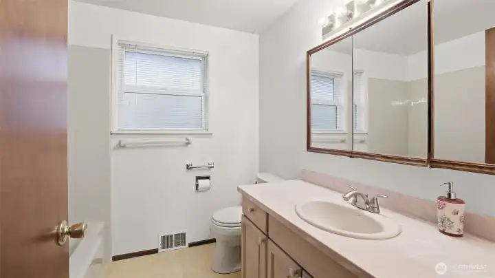 Bright and functional full bathroom with a large mirror and ample counter space.