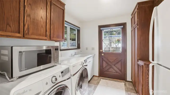Well-equipped laundry space featuring generous storage, full-size appliances, and a handy utility sink.