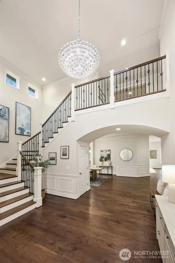 An impressive two-story foyer welcomes you with soaring ceilings and a striking statement chandelier. A custom staircase with iron balusters adds architectural elegance.