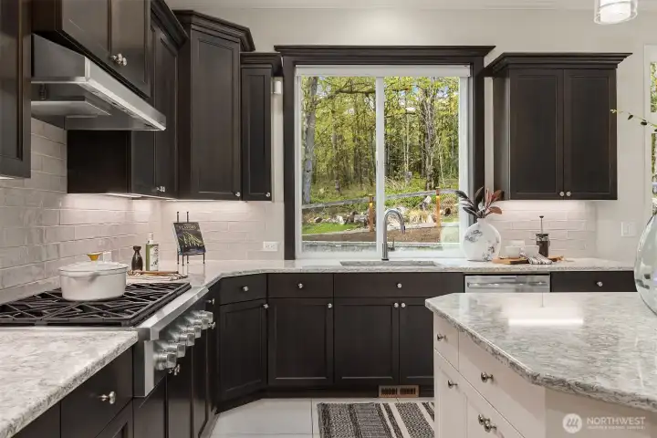 The chef’s kitchen features custom soft-close cabinetry, quartz slab countertops, and a handcrafted Zellige tile backsplash.