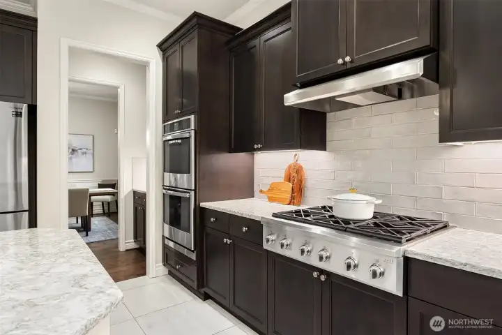 A 6-burner gas cooktop with hood aand double convection ovens, anchor the gourmet kitchen.