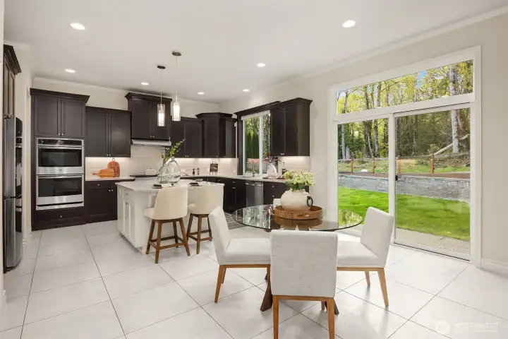 Wide sliding glass doors with a transom window frame the outdoor setting, offering a picturesque backdrop for casual dining.