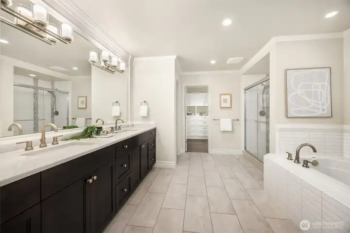 The spa-inspired primary bath is thoughtfully appointed with dual undermount sinks, quartz slab counters, custom tile, crown molding and a custom designed walk-in closet.