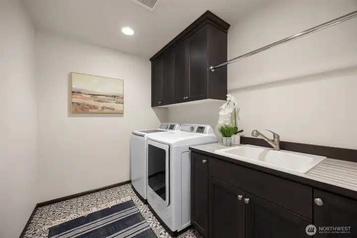 The well-appointed laundry room includes statement encaustic-style floor tile, a side-by-side washer & dryer, a utility sink and abundant storage for everyday convenience.