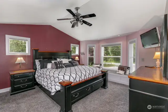 Primary bedroom with vaulted ceilings & bay window with window seat.