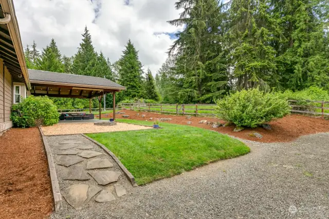 side yard with firepit & covered patio.