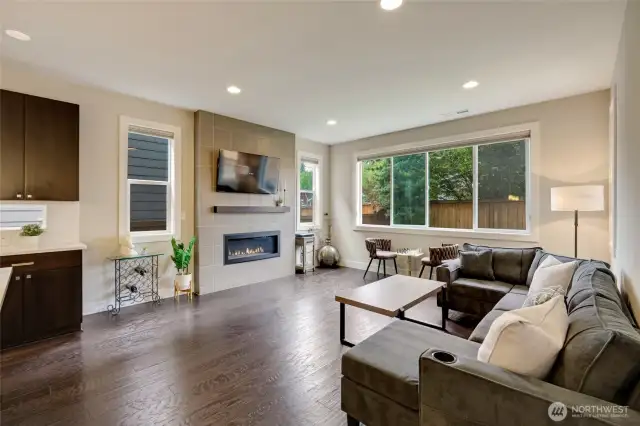 Main living area features pictures windows and cozy centerpiece fireplace.