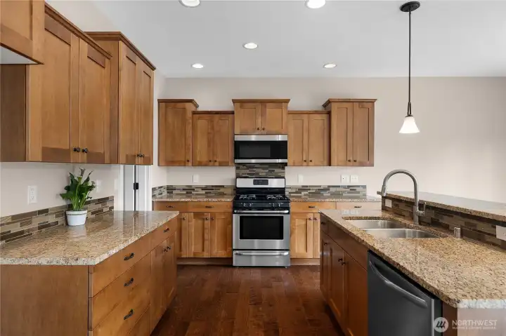 Bright kitchen with granite counterops, gas range with microwave, new dishwasher, and plenty of cabinets and prep space.