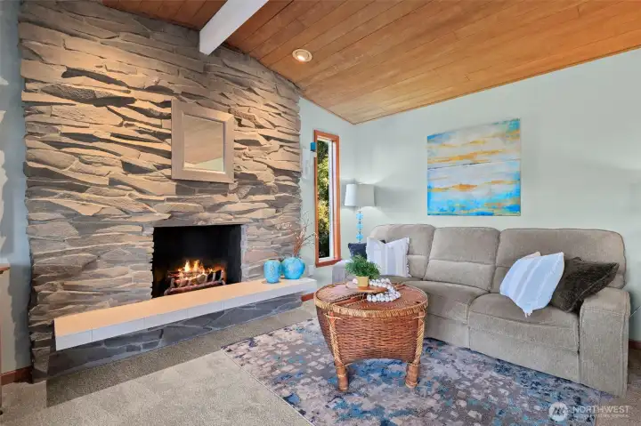 Rustic charm meets cozy comfort in this living room with stone wood-burning fireplace and patio access