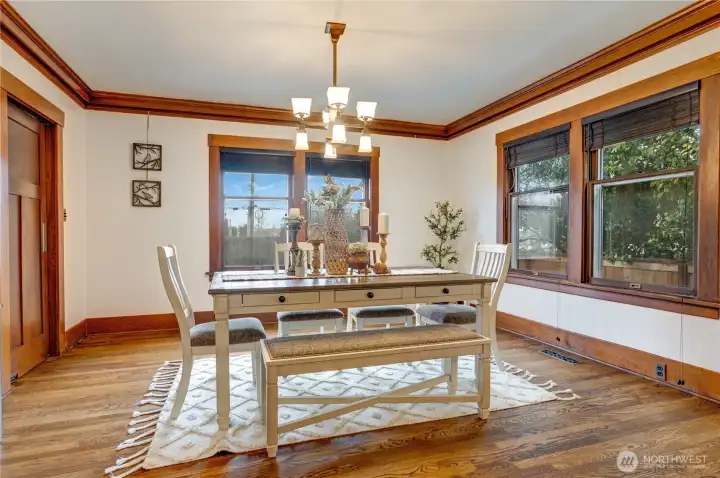 This spacious dining room invites gatherings with friends and family. Two sets of windows brighten the space, while the classic light fixture, picture rail, and wood-wrapped windows add warmth and charm.
