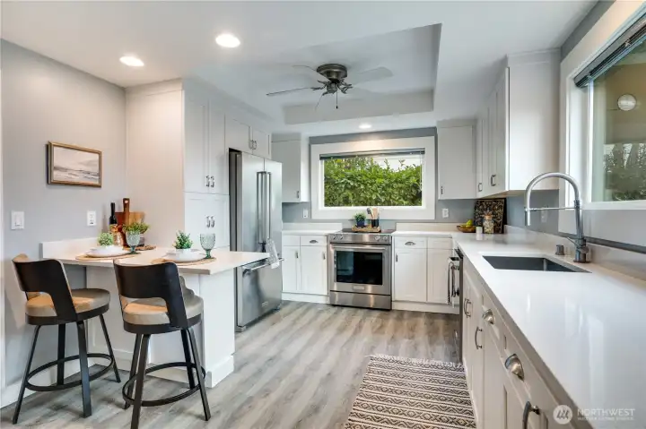 The updated kitchen shines with stainless steel appliances, sleek quartz countertops, a cozy breakfast bar, and a new luxury vinyl floor for easy maintenance.