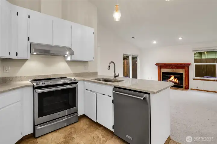 Kitchen with breakfast nook, heated floors, stainless steel appliances, vaulted ceilings, and quartz counters
