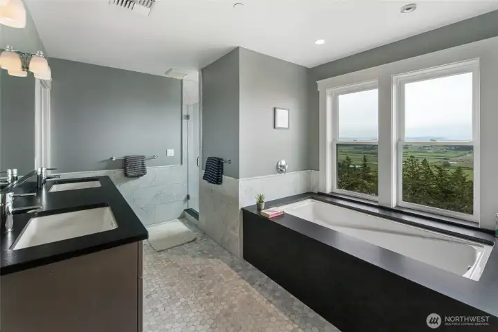 Spa-inspired primary bathroom with soaking tub, dual vanities, and sweeping San Juan Island valley and water views.