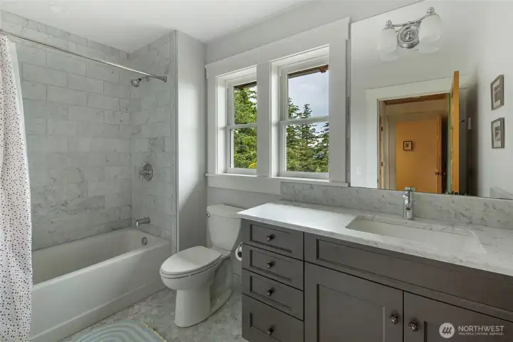 Light-filled guest bath with marble tile, modern fixtures, and quality finishes reflecting the home’s custom craftsmanship.