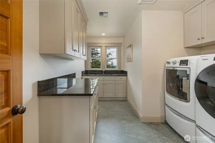 Convenient upper-level laundry room with storage and workspace, located near bedrooms for everyday ease.