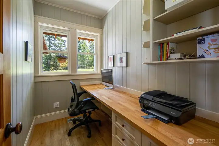 Dedicated home office with built-in desk and shelving, ideal for remote work in a quiet San Juan Island setting.